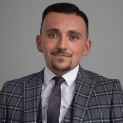A professional man smiling wearing a suit and tie.
