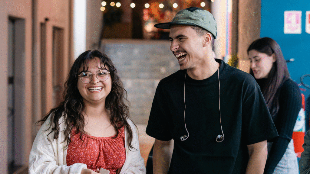 Two college students, one male and one female, walking down the hall laughing and smiling.