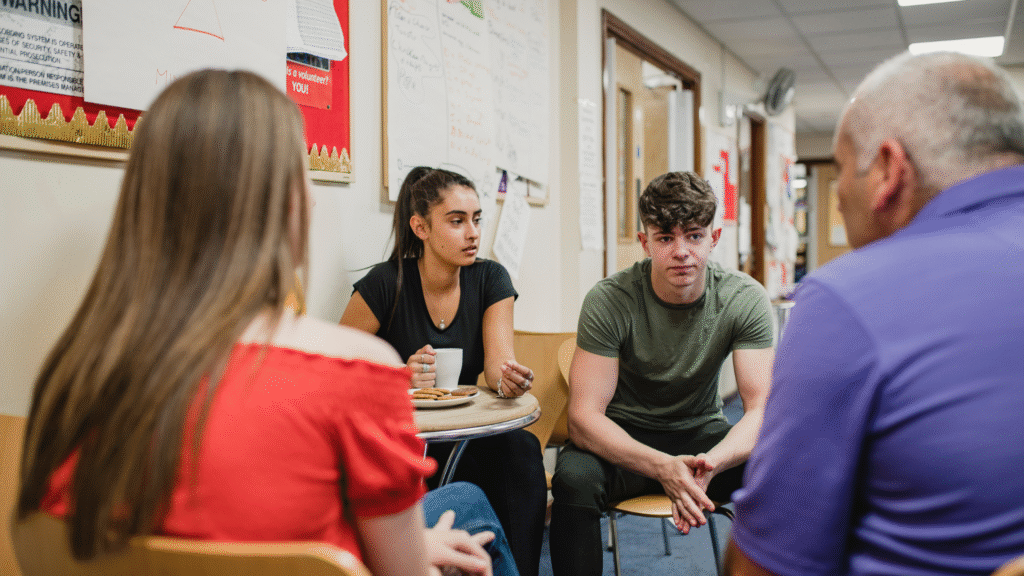 Two teenagers in a programme talking with two adults at a community centre.