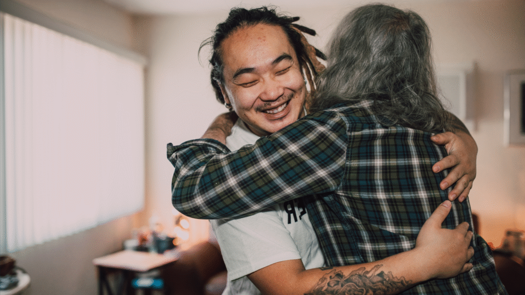 A man being hugged in celebration of learning new skills and a promotion, they are celebrating good news.