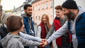 A youth group learning to become work ready as a team with hands in centre standing outside.