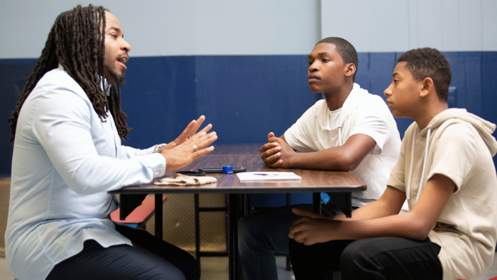 A mentor talking to two teenagers about his experience.
