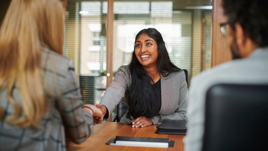 A young girl smiling and shaking hands with an interviewer after gaining an entry-level job.